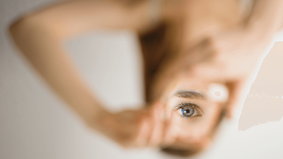 Woman peering through heart-shaped hands, selective focus.