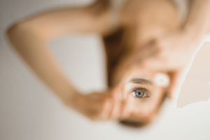 Woman peering through heart-shaped hands, selective focus.