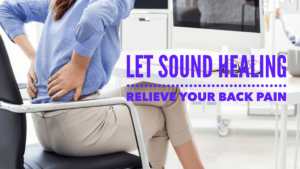 Person with back pain at desk considering sound therapy.