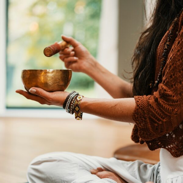 Woman using singing bowl for meditation and relaxation.