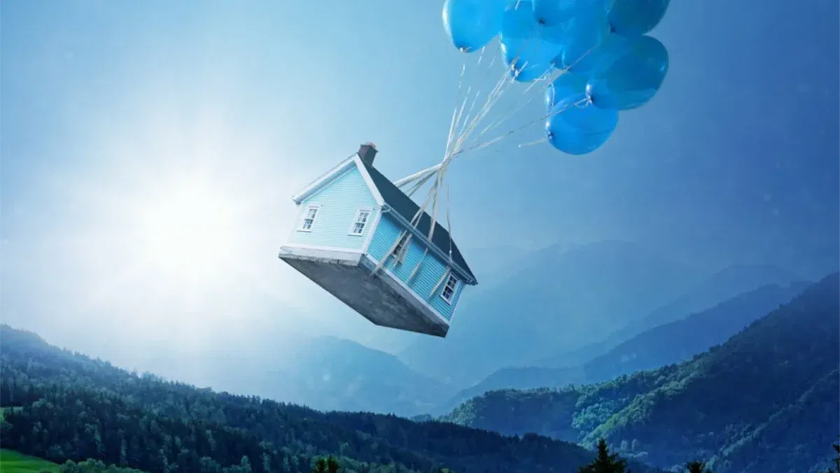 House floating with blue balloons over forest.