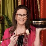 Smiling woman holding decorative singing bowl.