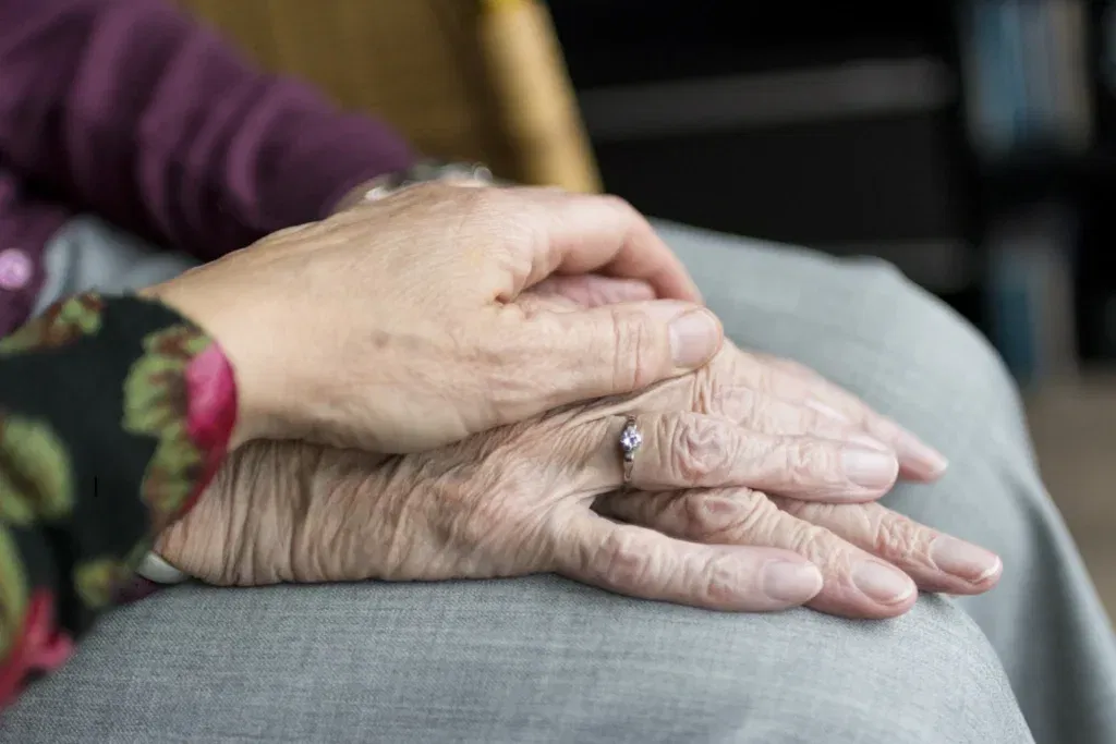 Elderly hands with a ring, showing comfort and care.