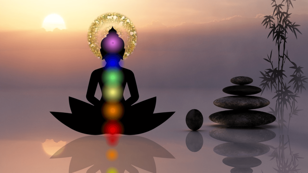 Meditating silhouette with chakras at sunset