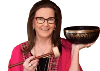 Woman holding singing bowl and mallet, smiling.