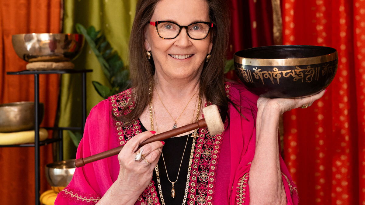 Woman holding singing bowl in colorful room.
