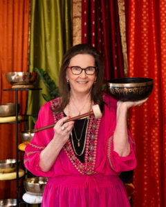 Woman holding singing bowl in colorful room.