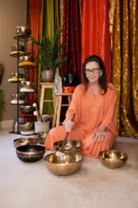 Woman playing Tibetan singing bowls in meditation space.