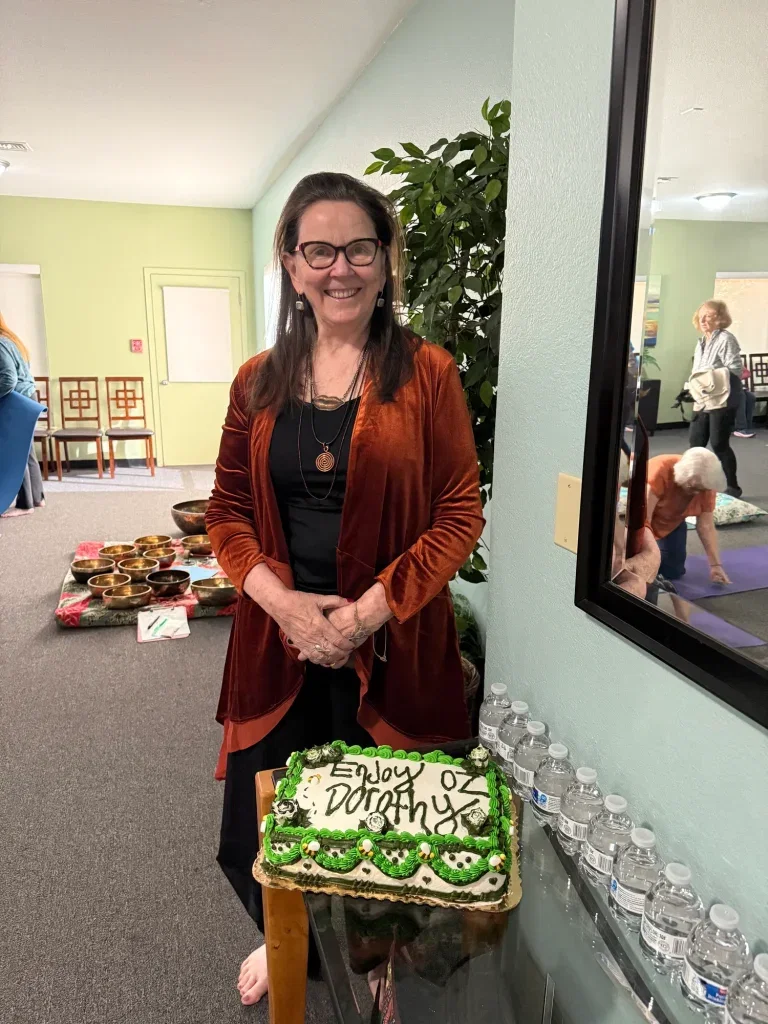 Woman standing behind decorated celebration cake indoors